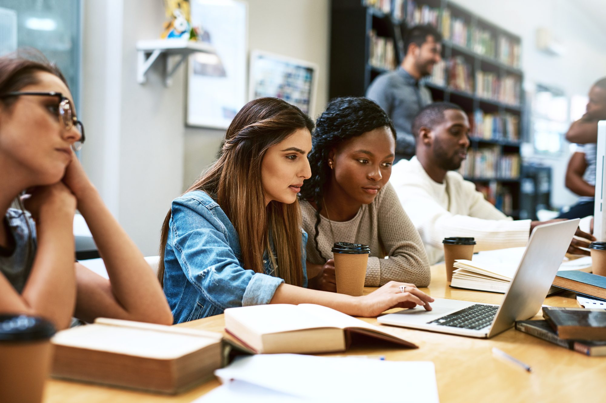 A group of people sitting at tables with books and laptops.