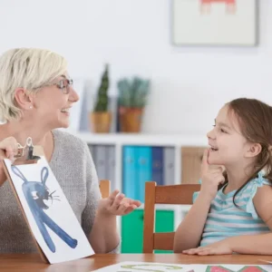 A woman and girl sitting at table with picture of bunny rabbit.