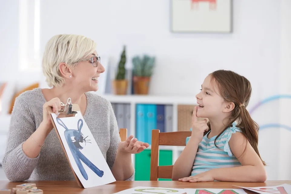 A woman and girl sitting at table with picture of bunny rabbit.