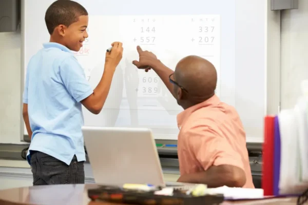 A man and boy are pointing at a whiteboard