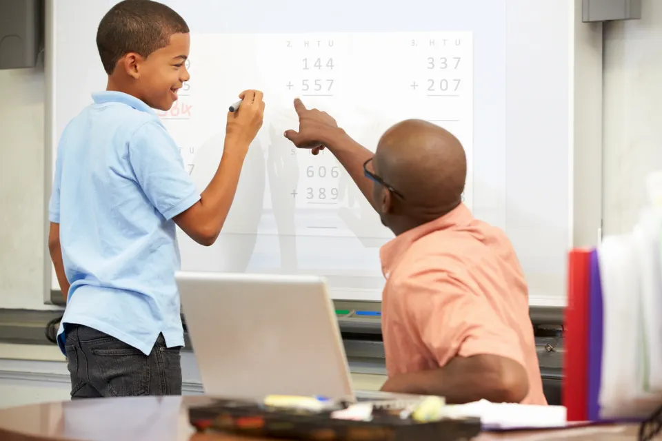 A man and boy are pointing at a whiteboard