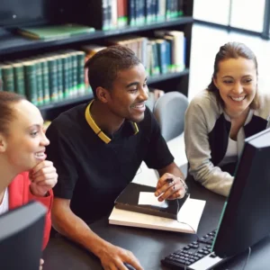 Three people sitting at a table with computers.